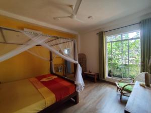 a bedroom with a canopy bed and a large window at Green Eyes Villa in Habaraduwa Central