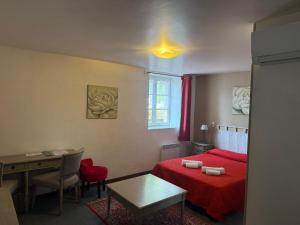 a small bedroom with a red bed and a table at HOTEL GALIMAR in Lamalou-les-Bains