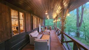 a porch of a wooden cabin with chairs and tables at Nad Lipcykiem in Nowy Gaj