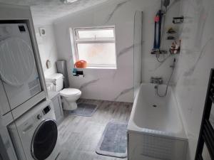 a bathroom with a tub and a toilet and a sink at Murston Double Room in Kent +7 photos