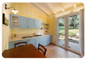 a kitchen with blue cabinets and a table with a tableablish at AGRITURISMO IL CARDO in Soiano del Lago