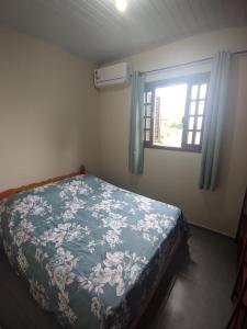 a bedroom with a bed with a floral bedspread and a window at Residencial Lumar in Itapoa +39 photos