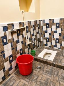 a bathroom with a toilet with a red bucket at Hotel Rajmahal in Ajmer