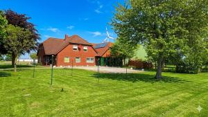 a red brick house with a tree in the yard at Ferienhof am Meer in Friedrichskoog