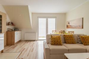 a living room with a couch and a kitchen at Apartament Malinowy-Osiedle Malinowa 68, Zieleniewo in Zieleniewo +4 photos