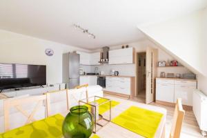 a kitchen with white cabinets and a table with a vase at Apartament Malinowy-Osiedle Malinowa 68, Zieleniewo in Zieleniewo