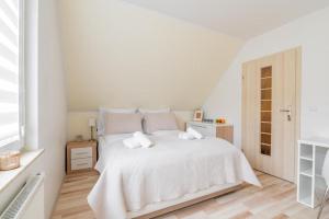 a white bedroom with a white bed and a window at Apartament Malinowy-Osiedle Malinowa 68, Zieleniewo in Zieleniewo