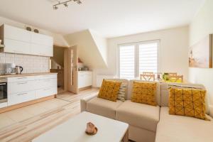 a living room with a couch and a kitchen at Apartament Malinowy-Osiedle Malinowa 68, Zieleniewo in Zieleniewo