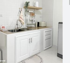 a white kitchen with a sink and a refrigerator at 50 m by BTS Taladplu in Thonhuri