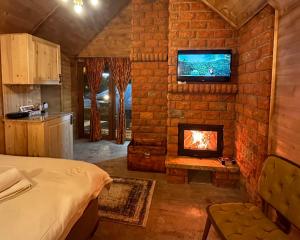 a bedroom with a fireplace and a tv on a brick wall at Malesia Eko Resort in Peje +110 photos