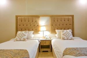 a hotel room with two beds and a lamp on a table at Petra Premium Inn in Wadi Musa +96 photos