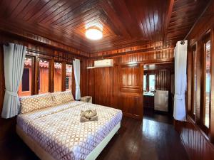 a bedroom with a bed in a wooden room at KT Thai House in Ban Ko Khwan