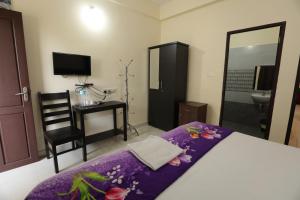 a bedroom with a bed and a chair and a television at Classique Inn Near Padmanabhaswamy Temple in Trivandrum