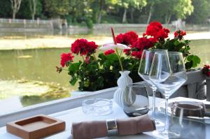 a table with wine glasses and red flowers on it at Hotel Restaurant Pavillon Bleu in Olivet +43 photos