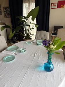 a white table with a blue vase with flowers on it at Chez Tantine Nadine in Couvin +7 photos