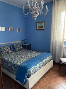 a bedroom with a bed with blue walls and a chandelier at B&B Villa Giardini Susanna in Veruno