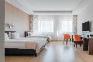 a hotel room with two beds and a television at Green Loft Gdynia in Gdynia