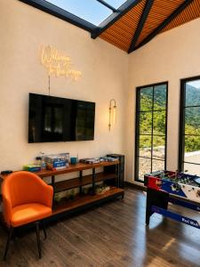 a living room with an orange chair and a television at Tiraya Luxury Riverside Hotel & Café in Gushaini