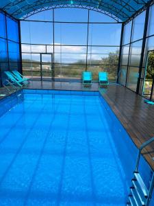 a large swimming pool with blue chairs in a building at Guest House Ugra in Barskoon
