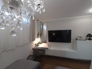 a white living room with a tv and a chandelier at Guesthouse EL in Ogulin