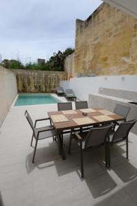 a patio with a wooden table and chairs next to a pool at KY Orange Grove in Kerċem