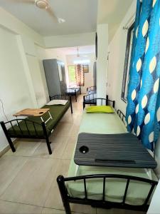 a room with three beds and a table and chairs at Alpine Hostel Services in Pune