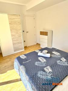 a bedroom with a bed with a blue blanket at APARTBEACH BLAU MAR y PORT AVENTURA in Salou