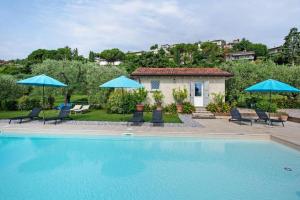a swimming pool with chairs and umbrellas and a house at AGRITURISMO IL CARDO in Soiano del Lago
