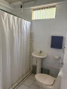 a white bathroom with a toilet and a sink at Villa Descanso in Colón