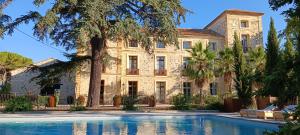 an exterior view of a large stone building with a swimming pool at domaine Les Castans in Saint-Thibéry