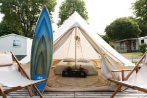 a tent with a surfboard and two chairs at Aparra Surfcamp Auberge Capbreton in Capbreton