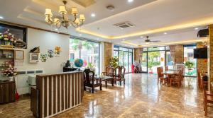 a living room with a table and chairs and windows at Xanh Tốt Hotel - FLC Sầm Sơn in Sầm Sơn