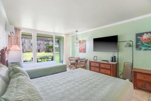 a bedroom with two beds and a flat screen tv at Garden Studio | Free Wi-Fi | No Resort Fees in Kapaa