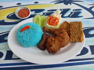 a plate of food with meat and vegetables on a table at Gili Davidoff Bungalow in Gili Trawangan