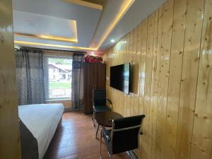 a bedroom with a bed and a table and a tv at Hotel Sounsar and Restaurant in Sonāmarg
