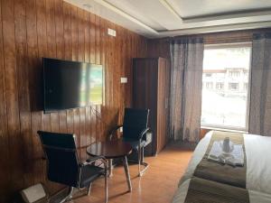 a hotel room with a bed and a television on a wall at Hotel Sounsar and Restaurant in Sonāmarg