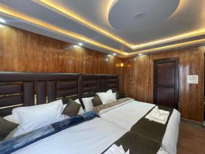 a bedroom with a large bed with a wooden wall at Hotel Sounsar and Restaurant in Sonāmarg +11 photos