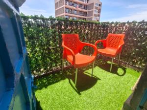 two orange chairs sitting on the grass in front of a fence at Meg Cozy Homes Executive 1Bedroom and 2Bedroom Apartments Near Rupa Mall The Noble Hotel & Poa Place Resort in Eldoret