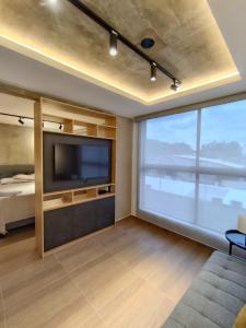 a living room with a tv and a large window at MOCA Living in Cali