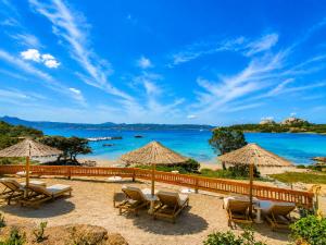 a beach with chairs and umbrellas and the ocean at Casa al mare Porto Sole in Baja Sardinia