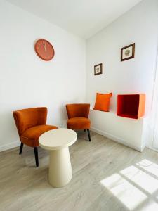 a room with two chairs and a table and a clock at Hyper centre, rue piétonne, calme et lumineux in Dijon