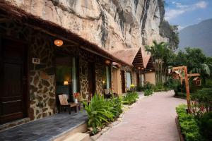 a building with a rock wall next to a sidewalk at Tràng An Valley Garden in Ninh Binh