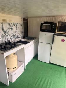 a kitchen with white cabinets and a refrigerator and a microwave at Chambre d'hôte Mles bêtes in Avensan