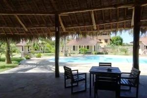 a patio with a table and chairs and a pool at Diani cozy cottage camp in Diani Beach +3 photos
