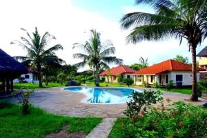 a resort with a swimming pool and palm trees at Diani cozy cottage camp in Diani Beach