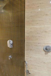 a shower with a yellow tiled wall with a shower head at Hotel Suites Inn in Mumbai