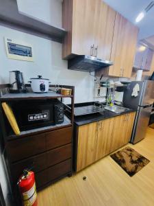 a kitchen with wooden cabinets and a black refrigerator at The Loop Towers Limketkai in Pontud