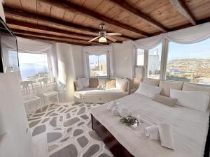 a bedroom with two beds and a couch and windows at Villa ELAYA in Mikonos