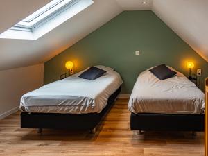 two beds in a attic bedroom with green walls at La Petite Mazure in Tournai