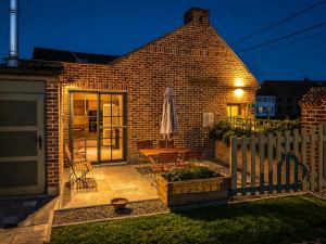 a brick house with a white fence and a patio at La Petite Mazure in Tournai